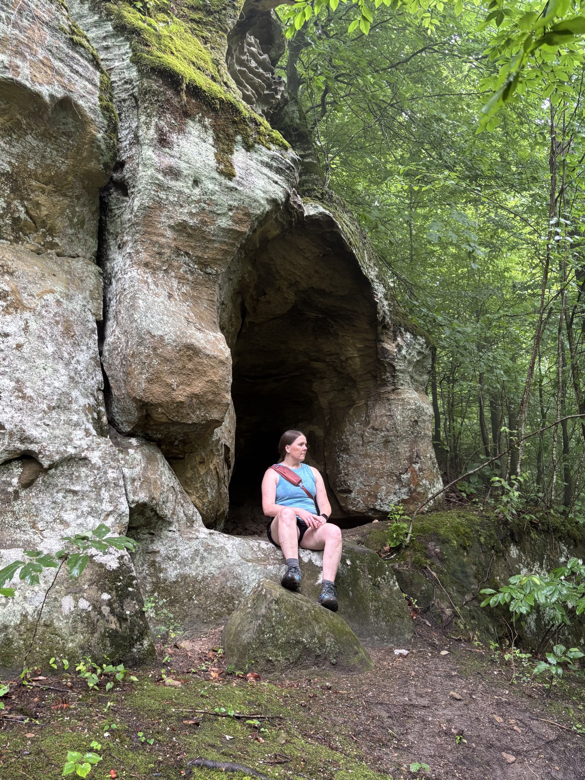 woman sitting on rock formation beside hiking trail